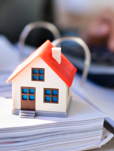 Photo of individual calculating finances with a model house on the desk